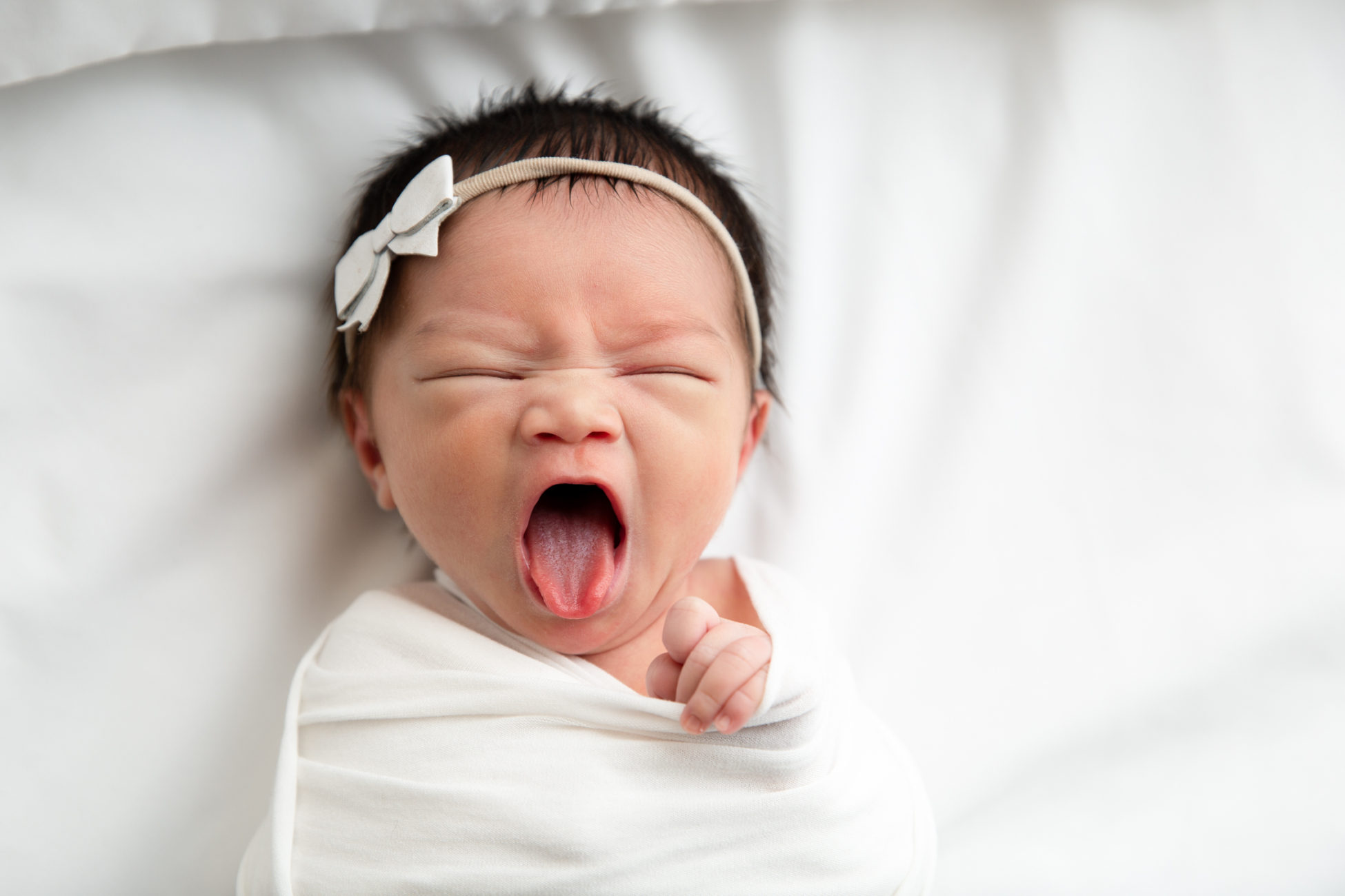 newborn baby yawning with tounge out
